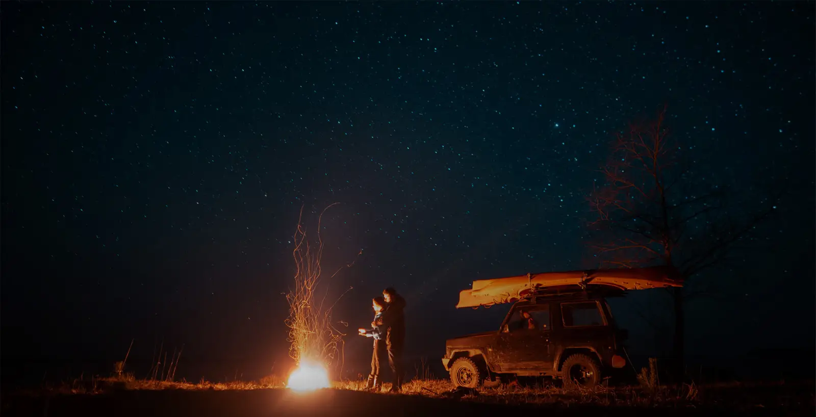 Camper-Van an einem Lagerfeuer bei Nacht