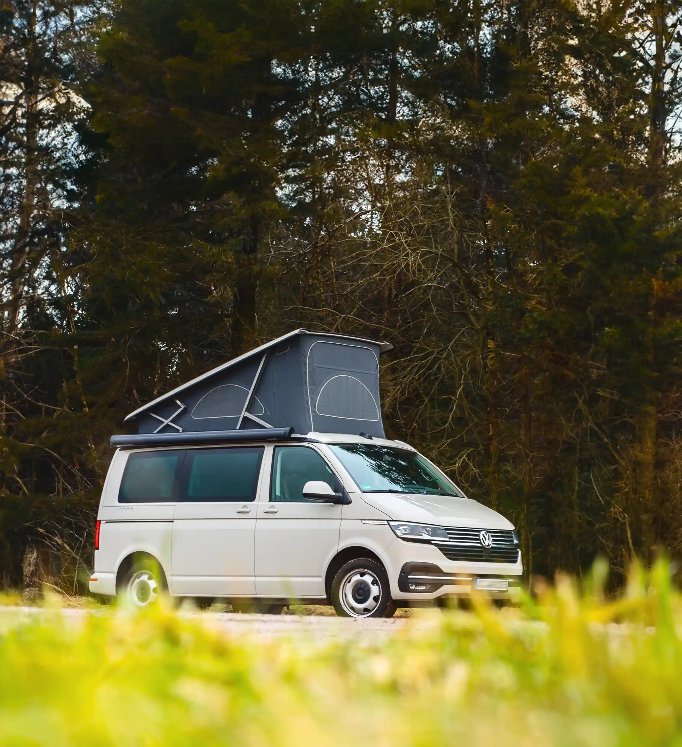 Kleiner Camper parkt vor einem Wald