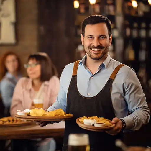 Glücklicher Kellner der Teller mit Essen hält und in die Kamera schaut