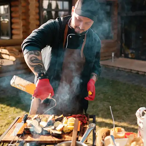 Ein tätowierter Koch ist bereit Gemüse und Fleisch zu grillen